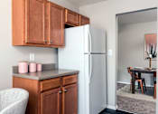 Thumbnail 21 of 29 - A kitchen with a refrigerator, wooden cabinets, and a chair.