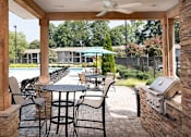 Thumbnail 13 of 29 - A patio with a table and chairs and a grill.