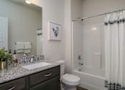Thumbnail 12 of 21 - Modern bathroom with granite vanity and tub at Liberty Point Apartments, Draper, UT 84020