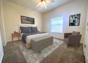Thumbnail 10 of 15 - Liberty Landing Apartments Heathrow Floor Plan double bed with night table and chair. West Jordan, Utah.