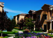 Thumbnail 6 of 15 - Liberty Landing Apartments flower bed with walking trails outside tan buildings. West Jordan, Utah.