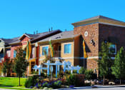 Thumbnail 4 of 15 - Liberty Landing Apartments entrance with flower beds and white wooden decorative structure. West Jordan, Utah.