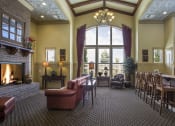 Thumbnail 8 of 15 - Liberty Landing Apartments large clubhouse with a fireplace, leather couches, bar seating and a large window