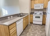 Thumbnail 8 of 18 - Liberty Bend Townhome Apartments, Sandy, Utah kitchen with white appliances and granite counter tops and wooden cabinets