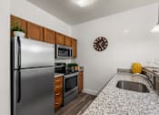 Thumbnail 4 of 34 - Compact kitchen with stainless steel appliances and granite countertops at Liberty Gateway Apartments, Salt Lake City, UT 84101
