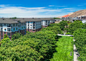 Thumbnail 33 of 34 - A row of apartment buildings with green trees in the foreground.