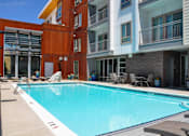 Thumbnail 13 of 30 - A swimming pool in front of a building with a red and white striped wall.
