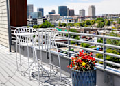 Thumbnail 12 of 30 - A patio with a table and chairs overlooking a city skyline.