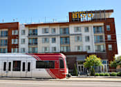 Thumbnail 29 of 30 - A red and white train is in front of a building with a sign that says "BROAD".