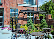 Thumbnail 15 of 22 - Liberty Gateway Apartments, Salt Lake City, Utah, a patio with a table and chairs is surrounded by green plants.