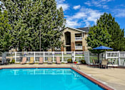 Thumbnail 14 of 23 - A swimming pool surrounded by a white fence and trees.