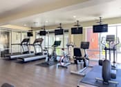 Thumbnail 20 of 30 - A gym with treadmills, exercise bikes, and weight machines.