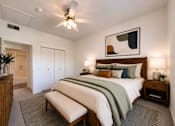 Thumbnail 19 of 20 - Liberty Landing Apartments, West Jordan, UT, bedroom with a bed, bench, and a ceiling fan.