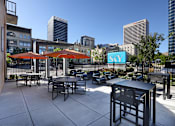 Thumbnail 35 of 41 - A patio with tables and chairs overlooking a cityscape.