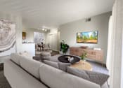 Thumbnail 12 of 23 - A living room with a grey couch and a painting of a forest on the wall.