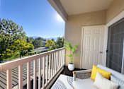 Thumbnail 10 of 23 - A balcony with a white couch and a potted plant.