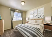 Thumbnail 1 of 23 - The Ridge at Jordan Landing Apartments, West Jordan, Utah, bedroom with wooden double bed, nightstands and lamps.
