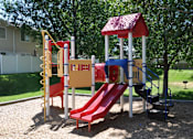 Thumbnail 18 of 23 - A playground with a red slide and a red and white swing set.