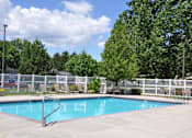Thumbnail 15 of 23 - A pool surrounded by a white fence and trees.