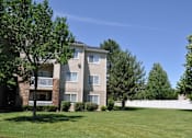 Thumbnail 20 of 23 - A large grassy area in front of a two-story apartment building.