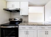 Thumbnail 5 of 19 - a kitchen with white cabinets and black appliances and granite counter tops at Palm Cove Apartments, Daytona Beach Florida