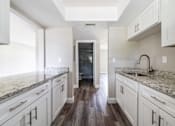 Thumbnail 4 of 19 - a kitchen with white cabinets and marble counter tops at Palm Cove Apartments, Daytona Beach, FL