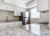 Thumbnail 7 of 19 - a kitchen with granite counter tops and a stainless steel refrigerator at Palm Cove Apartments, Daytona Beach, FL