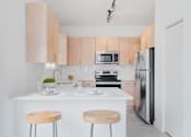 Thumbnail 6 of 29 - kitchen with wooden cabinets and a counter top with three stools