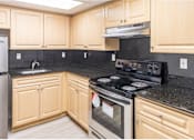 Thumbnail 5 of 15 - a kitchen with wooden cabinets and black granite countertops at Lakeside @ Biscayne Gardens,North Miami,33181