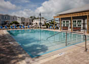 Thumbnail 21 of 24 - A pool surrounded by a brick patio and a wooden pavilion.