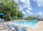 Thumbnail 21 of 22 - A pool surrounded by blue chairs and trees.
