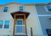 Thumbnail 16 of 24 - A yellow house with a white door and a balcony.