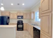 Thumbnail 3 of 24 - A kitchen with wooden cabinets and black appliances.