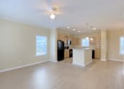 Thumbnail 5 of 24 - A spacious living room with a kitchenette in the background.