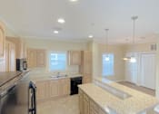 Thumbnail 4 of 24 - A kitchen with a black refrigerator and a black countertop.