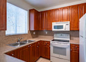 Thumbnail 9 of 29 - A kitchen with wooden cabinets and white appliances.