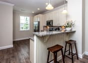 Thumbnail 5 of 20 - A kitchen with a granite countertop and wooden stools.