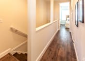 Thumbnail 6 of 20 - A hallway with wood floors and white walls.