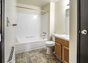 Thumbnail 11 of 17 - A bathroom with a white tub, toilet, and sink.