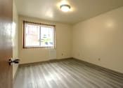 Thumbnail 6 of 17 - A room with a wooden floor and a window with blinds.