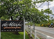 Thumbnail 1 of 15 - A sign for deMark Apartments is displayed by the roadside.