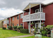Thumbnail 2 of 15 - A red building with a balcony and a small garden in front.