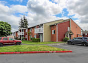 Thumbnail 3 of 15 - A red car is parked in front of a red brick building.