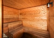Thumbnail 11 of 15 - A wooden sauna with a bench and a light on the wall.