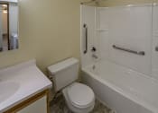 Thumbnail 9 of 15 - A white toilet sits next to a white bathtub in a bathroom.