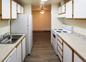 Thumbnail 5 of 15 - A kitchen with white appliances and wooden cabinets.