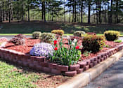 Thumbnail 15 of 16 - a beautiful spring garden in a brick containter at Village Square Apartments in Russellville, AL