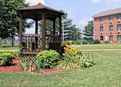Thumbnail 13 of 16 - a gazebo surrounded by plants in the courtyard of Village Square Apartments in Russellville, AL