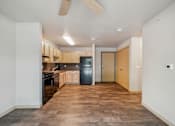 Thumbnail 14 of 26 - A kitchen with a black fridge and wooden cabinets.