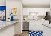 Thumbnail 4 of 41 - A kitchen with white cabinets and a blue rug.